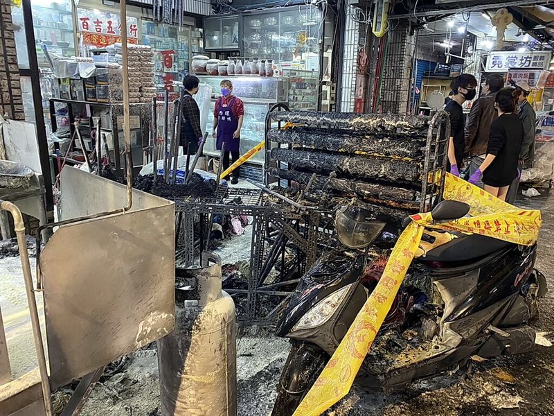 新北市土城區延吉街夜市11日傍晚驚傳火警,初步調查為某餐飲店一樓有客人機車未停好倒地,撞倒一旁瓦斯桶才引發大火燃燒,包括機車與商品與部分攤架都被焚燬,現場一片焦黑。(民眾黃小姐提供)中央社記者黃旭昇新北市傳真 113年1月11日