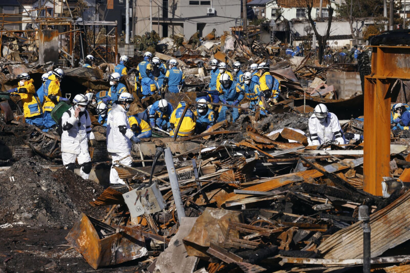 圖為日本救難人員11日在石川縣輪島市災區搜救。（共同社）
