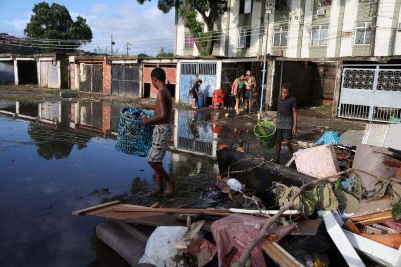 巴西里約熱內盧遭豪雨侵襲，居民14日在積水的街頭搬運物品。（路透社）