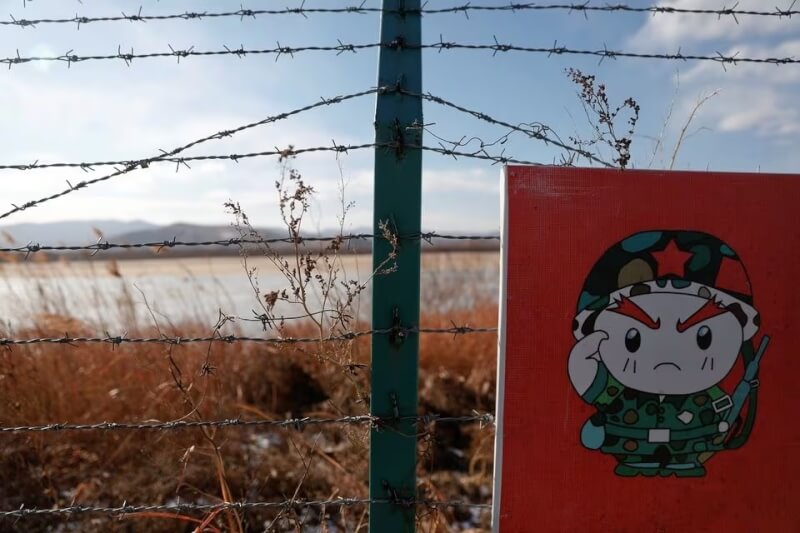 圖為2017年，中國、俄羅斯和北韓邊境，靠近中方一側的鐵絲網上掛有印著卡通士兵的警告標誌。（路透社）