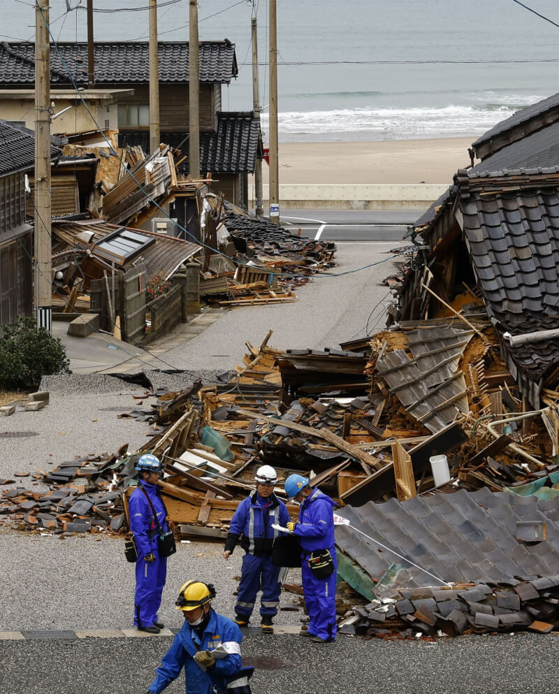 相關人員20日在石川縣輪島市災區搶修電力設備，四處可見遭地震毀損民房。（共同社）