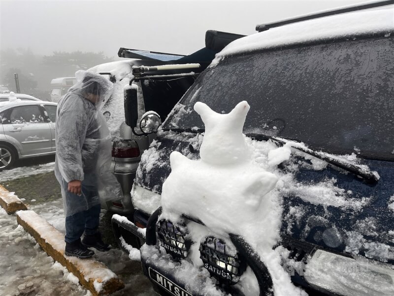 寒流影響，23日清晨大屯山已有降雪情形，低溫且有風雨，民眾在車上堆出了一個小雪人。中央社記者徐肇昌攝 113年1月23日
