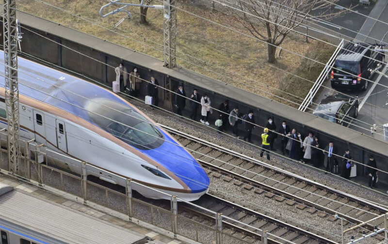 日本北陸新幹線列車23日被迫停駛，乘客沿著軌道行走。（共同社）