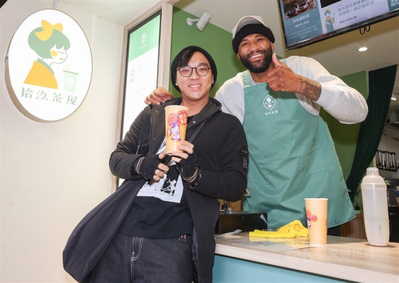 效力台灣職籃T1聯盟台啤永豐雲豹的前美國職籃NBA球星卡森斯(DeMarcus Cousins)(右)受邀擔任手搖飲一日店長,限量100杯「表弟奶茶」特別請藝術家Jeff(左)設計杯身小貼圖,看到成品的卡森斯相當滿意。中央社記者張新偉攝 113年1月26日