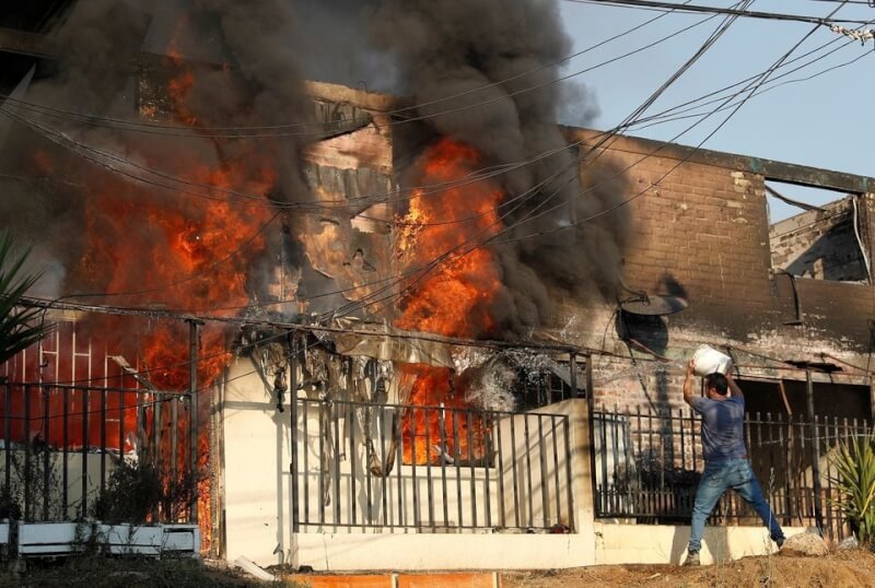 圖為2月智利比納薩瑪森林大火延燒民宅，1名男子試圖撲滅火勢。（路透社）