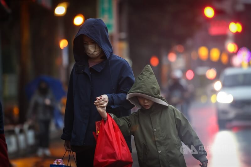 圖為新北市樹林區街頭民眾穿著厚外套、拉起帽子禦寒。（中央社檔案照片）