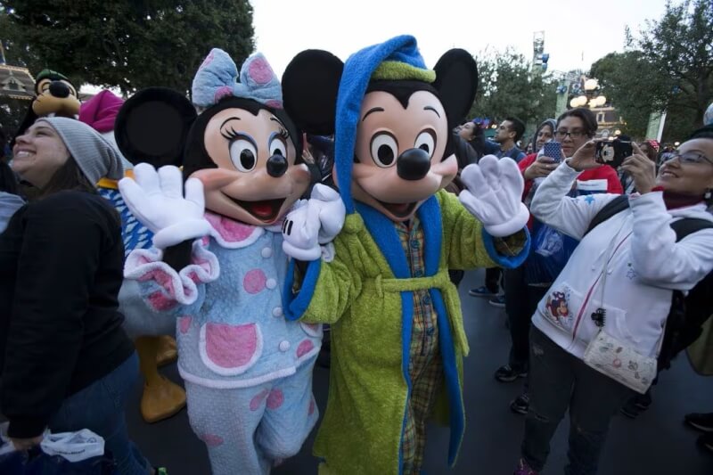 圖為加州迪士尼樂園的米老鼠人偶迎接遊客。（路透社）