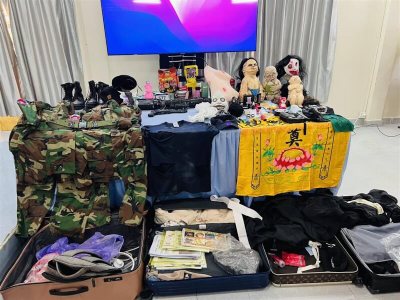 柬國警方15日將「晚安小雞」與網紅阿鬧押至記者會現場,並陳列相關證物,包括迷彩服、黑皮靴、鬼面具等。(讀者提供)中央社記者陳家倫河內傳真 113年2月15日