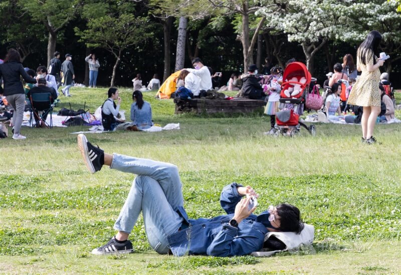 圖為台北市華山大草原有民眾戴著口罩躺在草地上，享受好天氣。（中央社檔案照片）