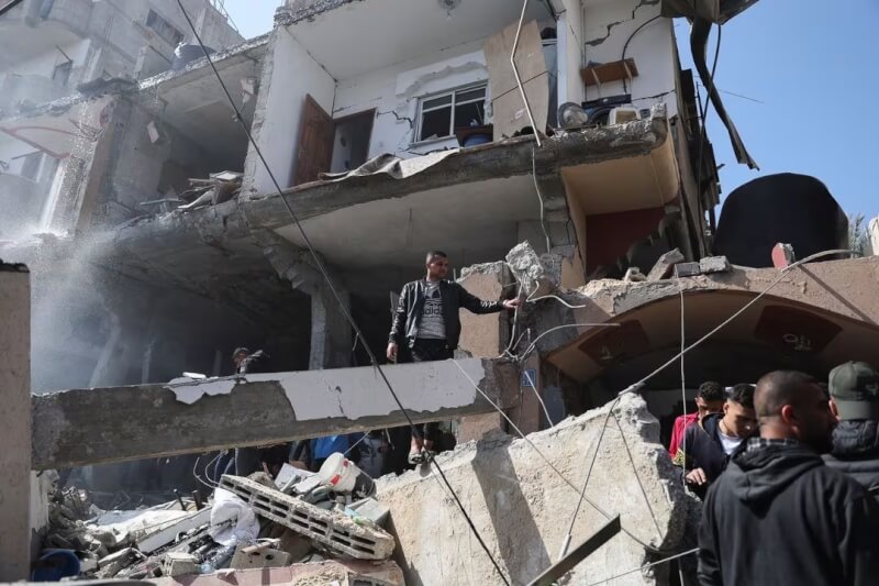 圖為24日巴勒斯坦人查看被以色列轟炸的建物。（路透社）