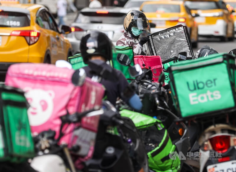 Uber Eats、foodpanda外送員在台北市中山區路邊臨停接單準備送餐。（中央社檔案照片）