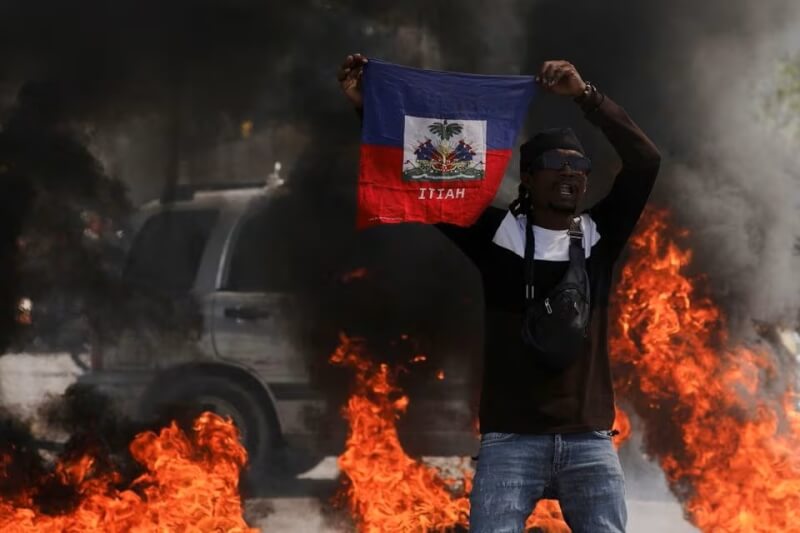 海地首都太子港1日街頭發生暴力示威，民眾高舉海地國旗。（路透社）