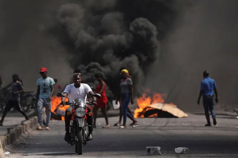 圖為海地太子港民眾1日行經燃燒的路障。（路透社）