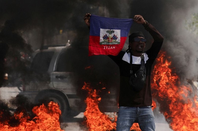 圖為1日示威民眾高舉海地國旗，對政府和社會局勢表達抗議。（路透社）