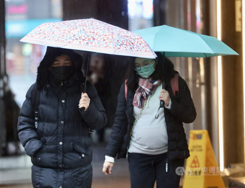 图为台北市中正区外出民众穿著厚外套，撑伞挡雨。（中央社档案照片）