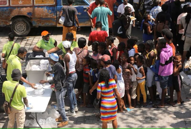 海地太子港暴力冲突恶化，居民4日在避难所领取餐点。（路透社）