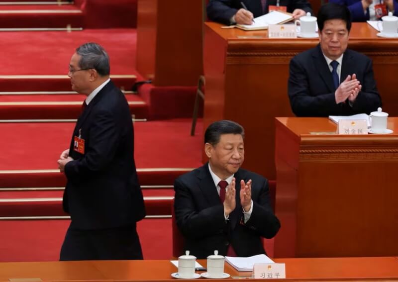 中國全國人大會議5日在北京人民大會堂舉行，國務院總理李強（左）走過國家主席習近平（前）身旁。（路透社）
