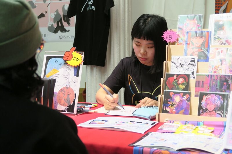 漫畫家Eli Lin依萊參加紐約漫畫及卡通博物館藝術節,17日在台灣展位擔綱「似顏繪」活動,現場繪製畫像。中央社記者尹俊傑紐約攝 113年3月18日