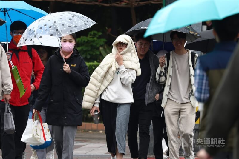 圖為台北市中正區有民眾以外套遮擋雨勢。（中央社檔案照片）