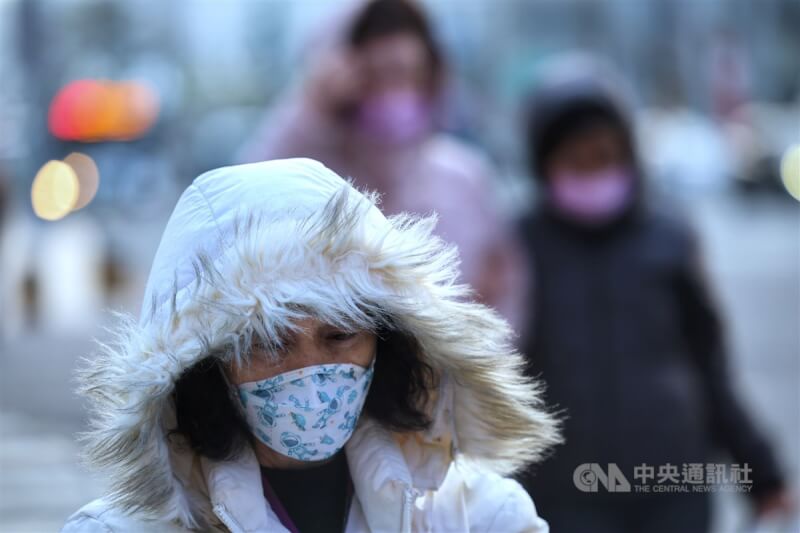 圖為台北市信義區街頭民眾拉起外套帽子擋風防寒。（中央社檔案照片）