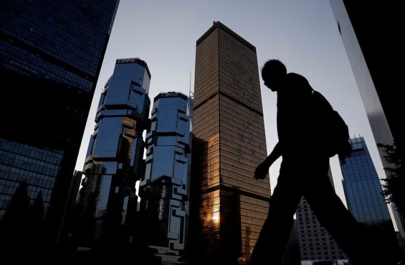 图为一名男子行经香港商业区的高楼大厦。（路透社）