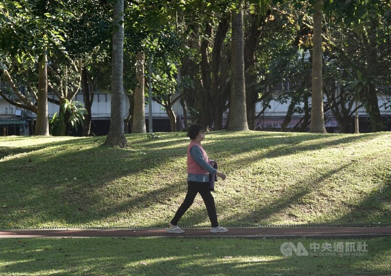 圖為民眾在台北市南港區公園散步，溫暖陽光從林間灑落。（中央社檔案照片）