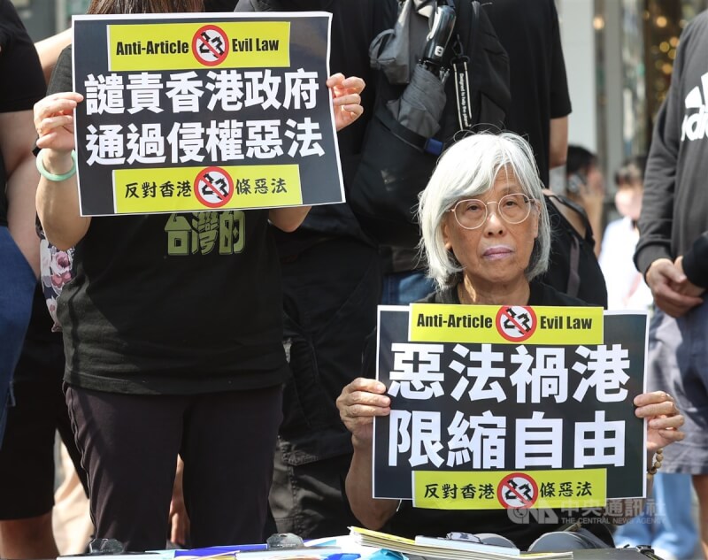 與會者手舉「譴責香港政府通過侵權惡法」、「惡法禍港限縮自由」等標語表達立場。中央社記者謝佳璋攝 113年3月23日