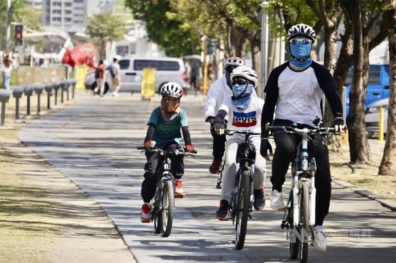 圖為騎單車的民眾著袖套、面巾防曬，赴高雄大港橋周邊遊憩。（中央社檔案照片）