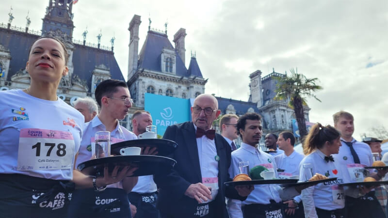 巴黎24日舉辦「咖啡館侍者競賽」，200名參賽者托著裝有飲料和可頌的托盤，盡力保持平衡向前衝。（圖取自twitter.com/PierreRabadan）