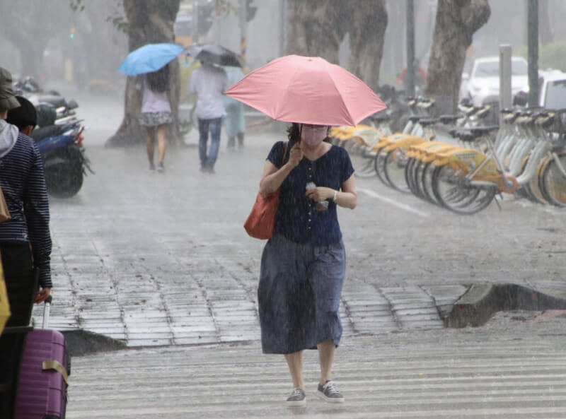 圖為高雄市苓雅區出現雨勢，民眾撐傘避雨。（中央社檔案照片）