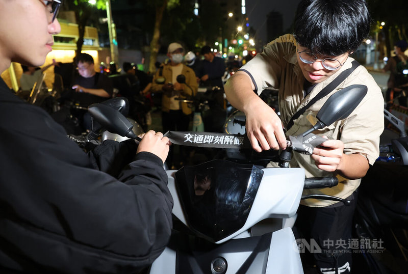 台灣機車路權促進會30日晚間在立法院前發起「路邊臨停不放任,禁行惡法應廢除」機車遊行,並製作「交通即刻解嚴」等標語布條發送給與會騎士。中央社記者趙世勳攝 113年3月30日