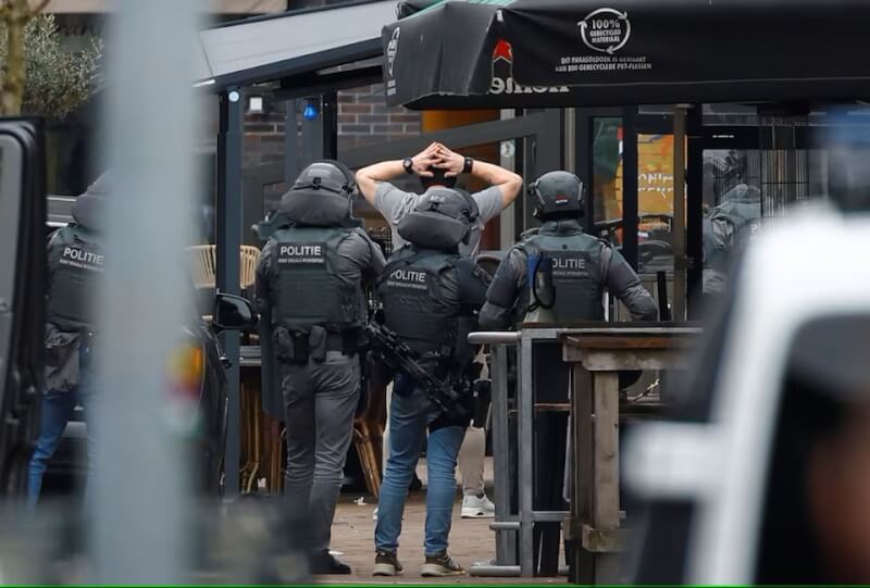 戴蒙面頭套的男嫌30日走出荷蘭東部市鎮的「襯裙咖啡」酒吧向警方投降，旋即被捕。（路透社）
