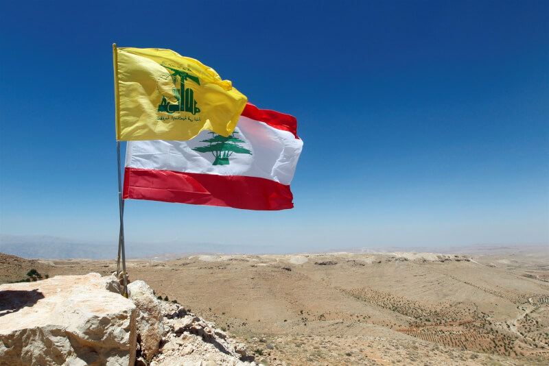 圖為黎巴嫩國旗（後）與真主黨旗幟（前）。（路透社）