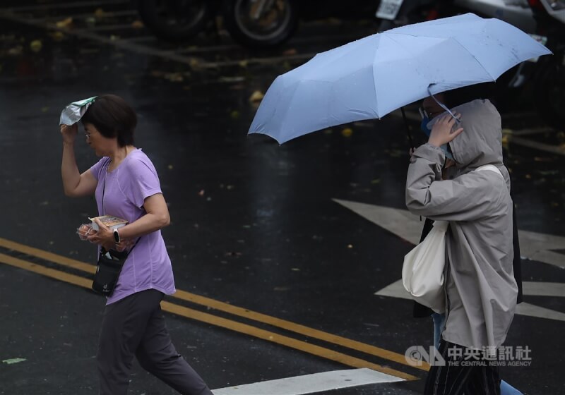 图为台北市松山区民众以手、伞遮挡雨过马路。（中央社档案照片）