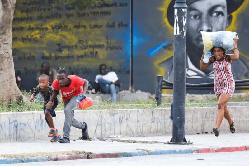 在路上遭遇槍戰的海地民眾正尋找掩護。（路透社）
