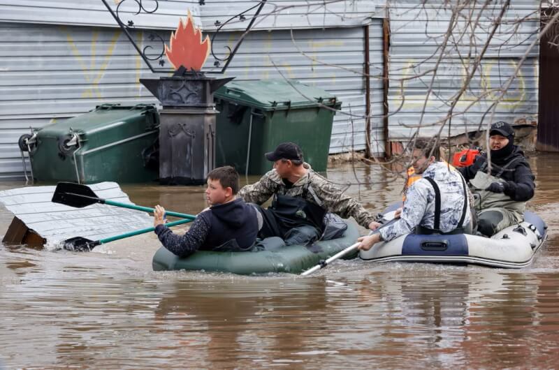 俄羅斯奧倫堡市居民10日在洪水中靠著橡皮艇移動。（路透社）