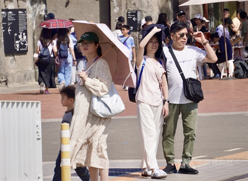 图为高雄市盐埕区出游民众，有人撑伞、拿起薄外套遮阳。（中央社档案照片）