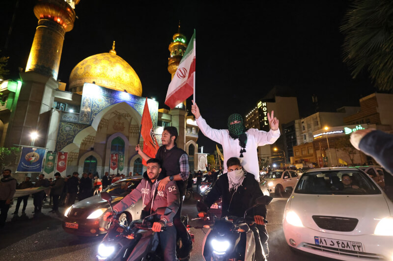 伊朗對以色列發動攻擊，有伊朗民眾14日在德黑蘭巴勒斯坦廣場揮舞伊朗國旗和巴勒斯坦旗幟。（法新社）