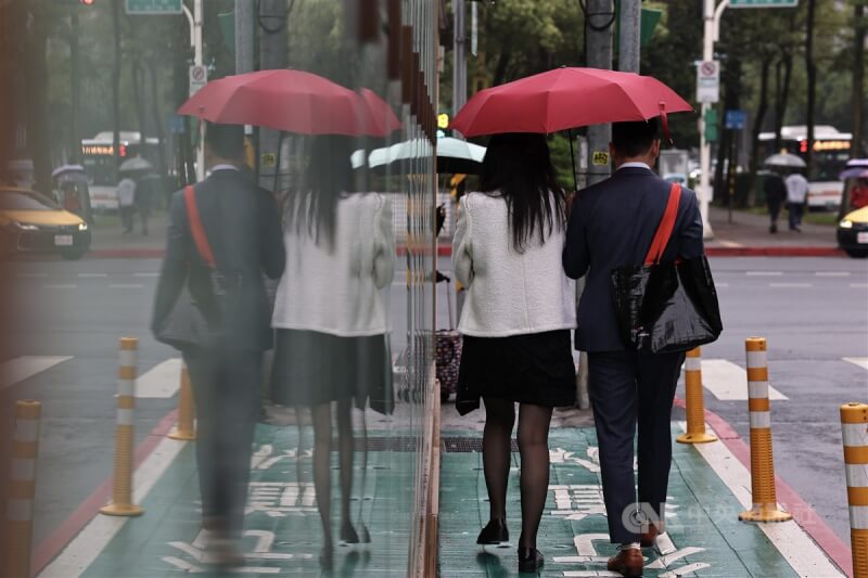圖為台北市信義區民眾撐傘擋雨。（中央社檔案照片）