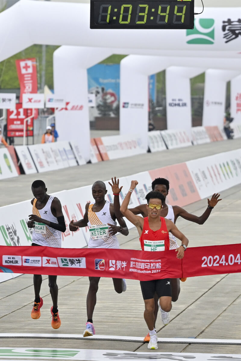 2024年北京半程馬拉松賽14日舉行，男子組中國選手何杰（前）以1小時3分44秒的成績率先衝線奪冠。（中新社）