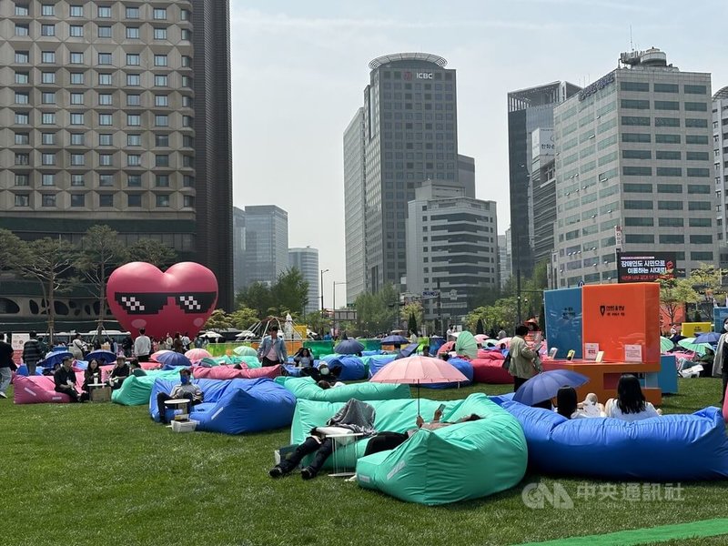 韩国首尔市政府举办的露天图书馆活动，为提升民众阅读体验，今年在首尔广场设置特地订做的2到3人用大型懒骨头沙发，以及阳伞等设备。中央社记者廖禹扬首尔摄  113年4月21日