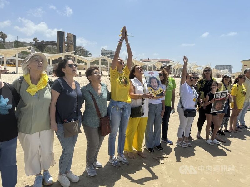 以色列被綁架人質謝姆托夫的母親雪莉（中，高舉雙手者）發起沿著以色列海灘形成人鏈的活動，成千上萬的以色列人加入。中央社記者賴素芬赫茲利亞市攝 113年4月22日