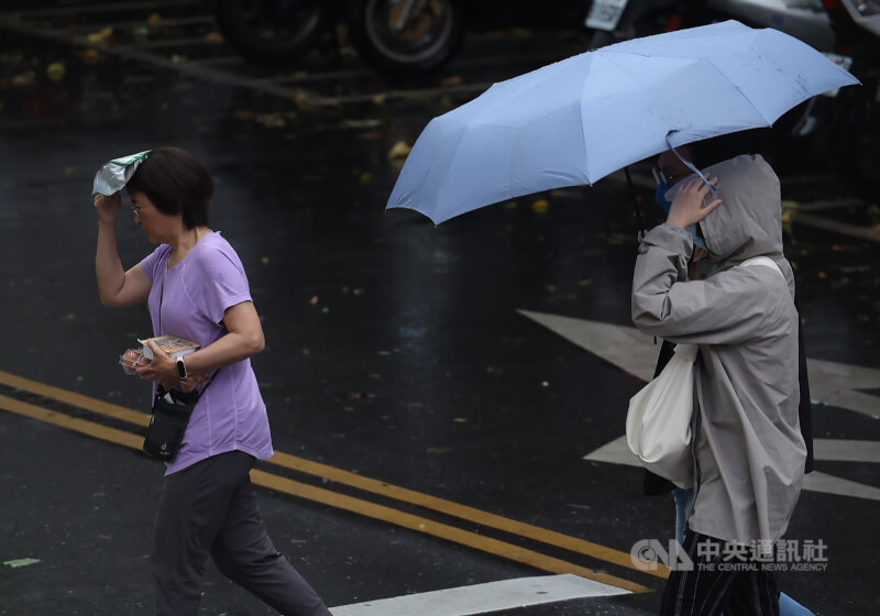 图为台北市松山区突然下起大雨，民众以手遮挡，快步过马路。（中央社档案照片）