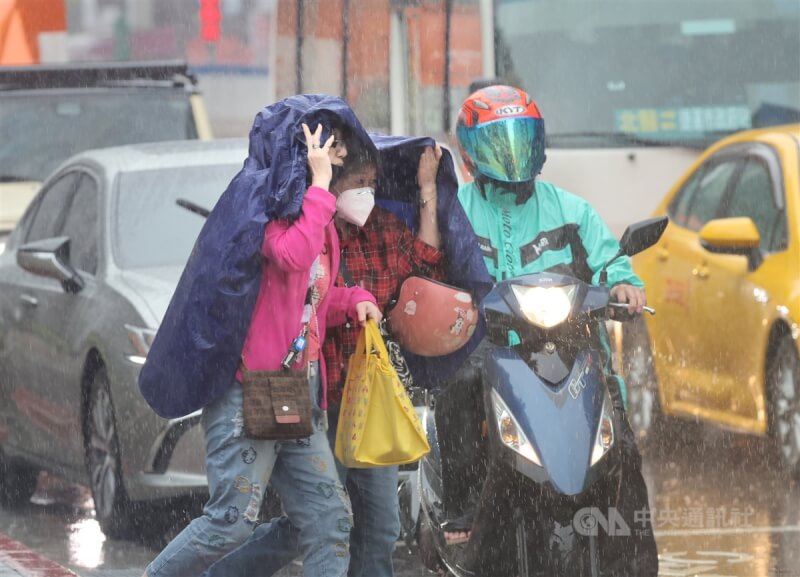 受锋面影响，台北市区26日中午一度下起大雨，信义区街头有民众没带雨伞，先以雨衣遮挡头部，快速通过马路。中央社记者王飞华摄 113年4月26日