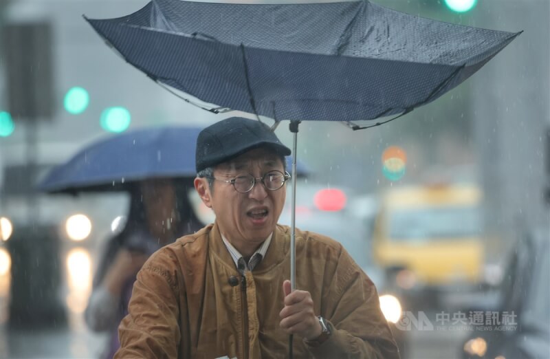 信義區有民眾撐傘走在街頭，手中雨傘被強風吹開了花。（中央社檔案照片）