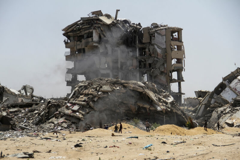 图为22日加萨走廊北部，巴勒斯坦人走过被以色列袭击的大楼废墟。（路透社）