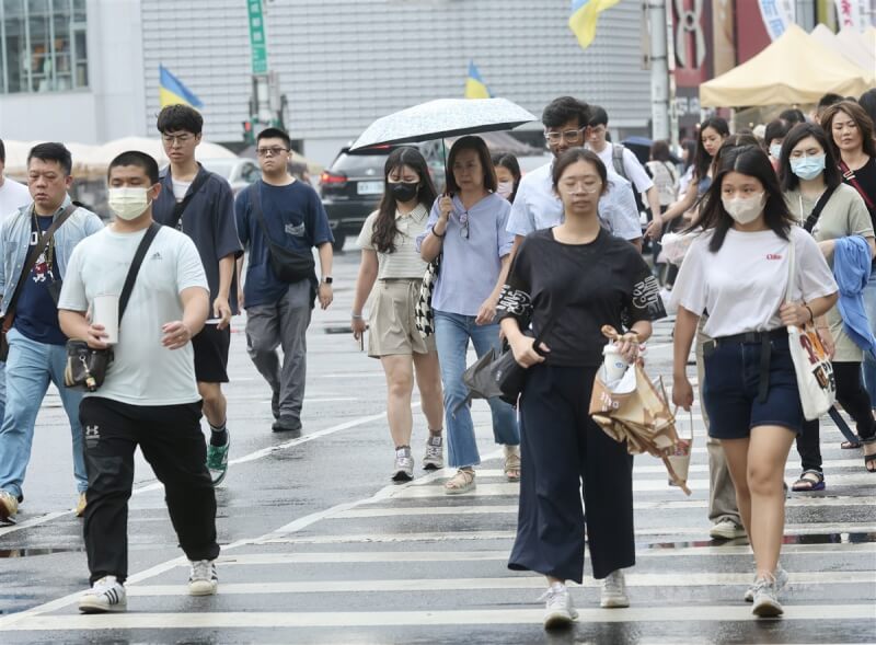 台北市區不時飄下陣雨，西門町街頭民眾有人撐著傘留意雨勢。（中央社檔案照片）