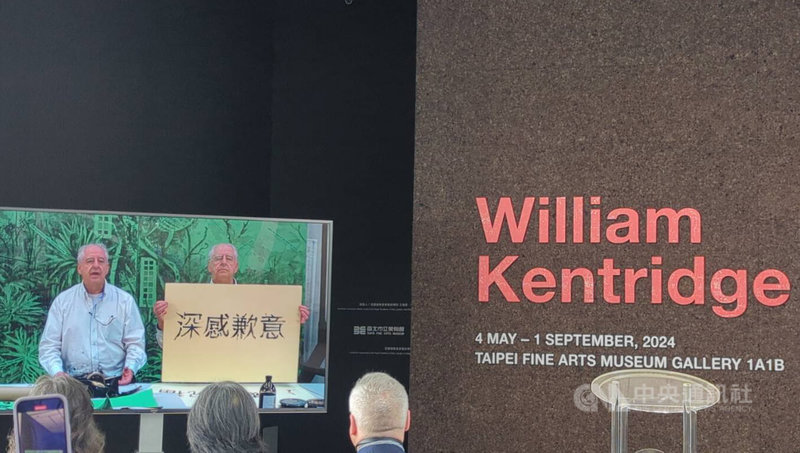 台北市立美术馆2日举行南非艺术家肯特里奇（William Kentridge）个展开幕记者会，肯特里奇特别录制影片献上祝福，且幽默地在影片中「分身」成2人，一个不断在纸上书写、并举起写著中文字「深感歉意」、「诚心祝福」、「谢谢你」的手举牌，向台湾观众致歉自己未能在开幕到场，并祝福展览顺利。中央社记者王宝儿摄  113年5月2日