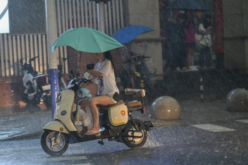 圖為4月27日廣東省廣州市下起暴雨，民眾在雨中騎車。（中新社）