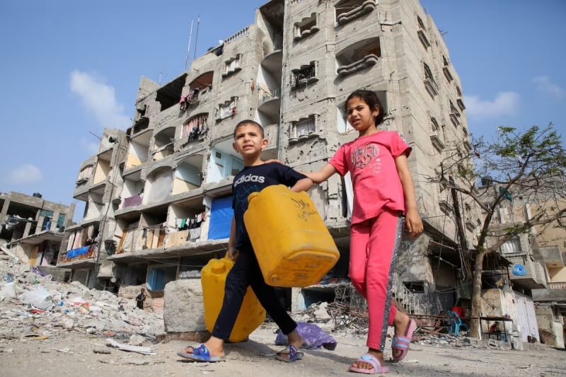 加薩南部拉法的巴勒斯坦孩童走過一棟因空襲遭摧毀的建築物。（路透社）